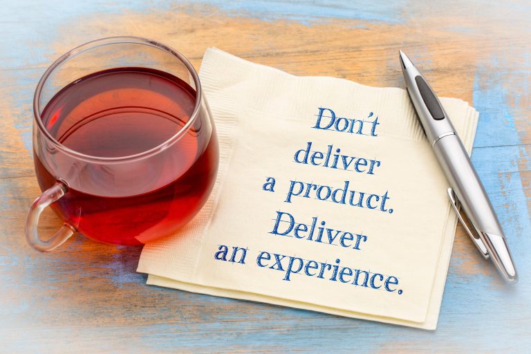 Don't deliver a product. Deliver an experience. Handwriting on a napkin with a cup of tea